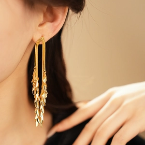 Macro detail of gold-plated leaf tassel earrings showing textured fringe and metallic shine