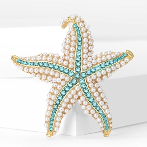 Detailed macro view of starfish brooch with white pearls and blue rhinestones on gold base