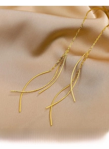 Macro shot of gold tassel drop earrings on champagne silk fabric background