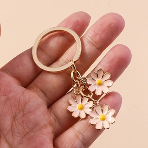 Detail of pink enamel daisy flower charms on a gold-plated metal keychain accessory