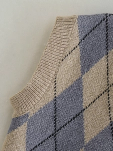 Detail of argyle knit vest featuring ribbed edges and soft gray-blue texture