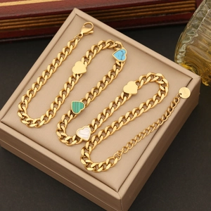 Close-up of three gold stainless steel heart bracelets with blue, green, and white charms