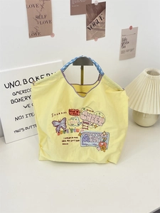Detailed view of yellow canvas tote bag with butterfly embroidery and woven handles
