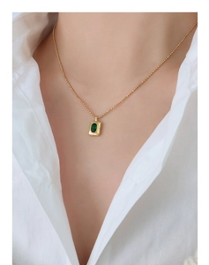 Detail of a vintage gold necklace featuring a luxury oval green gemstone pendant on model