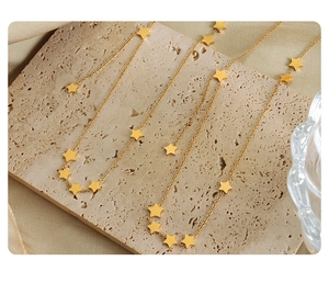 Detail of gold star pendant necklace on a travertine stone with warm lighting