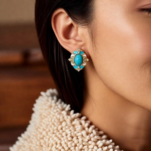 Gros plan de boucles d'oreilles vintage turquoise et émail blanc sur un mannequin