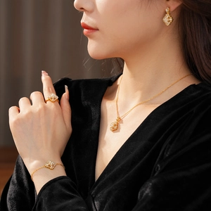 Détails d'un ensemble de bijoux en perles dorées porté avec un design de trèfle chic