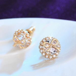 Macro detail of gold bow stud earrings with sparkling round zircon halo settings