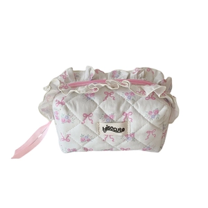 Quilted floral makeup bag with pink bow accents and ribbon details on white cotton fabric