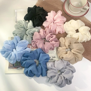 Set of 9 oversized chiffon scrunchies in pastel colors arranged on an elegant desktop