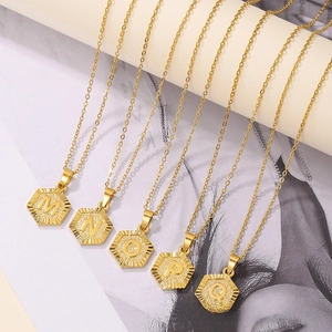 Macro detail of gold hexagon initial pendants with radial textures and O-chains