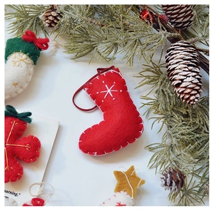 Detail of red wool felt Christmas stocking and star ornament with embroidered snowflake
