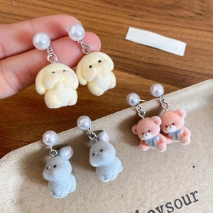 Detail shot of flocked rabbit and bear earrings with pearls on a display tray