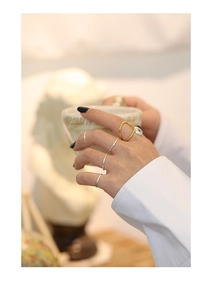 Close-up of stacked hammered silver bands and a bold gold irregular ring on a hand