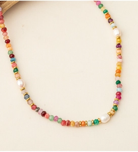 Macro detail of natural stone beads and white freshwater pearls on a gold necklace