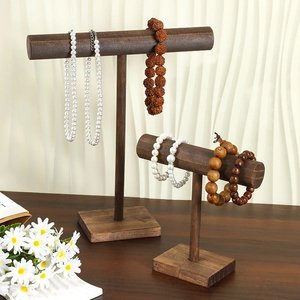 Rustic dark wood T-bar jewelry stands showcasing pearl necklaces and beaded bracelets