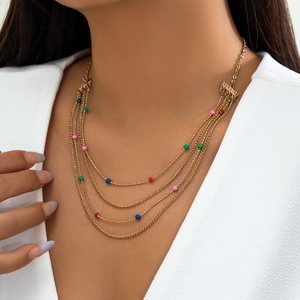 Close-up of gold layered necklace set with colorful beads on a v-neck outfit