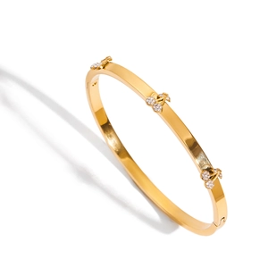 Gold stainless steel hinged bangle featuring three sets of crystal cherry charms on top