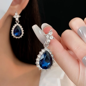 Macro detail of teardrop blue stone earrings with diamond halo and silver base