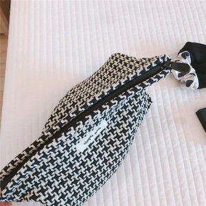 Detailed view of houndstooth plaid makeup bag with premium zipper and brand logo tag