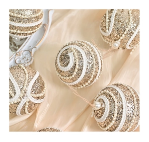 Close-up of gold sequined Christmas ball with white lace trim and pearl accents