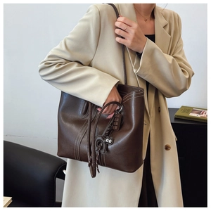 Detail of dark brown leather tote bag with white contrast stitching and cat charm