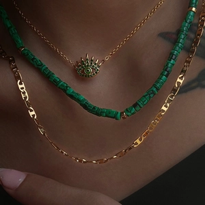 Three-layer layered necklace with green evil eye pendant and malachite beads on a model