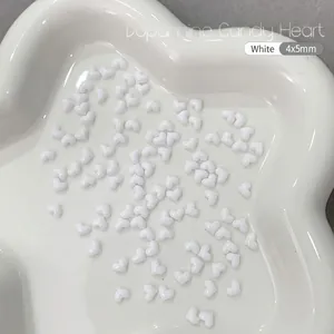 Macro shot of 4x5mm white heart resin nail art charms and DIY accessories in a dish
