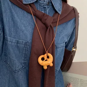 Detail of pretzel-shaped resin pendant necklace with minimalist face on knitwear
