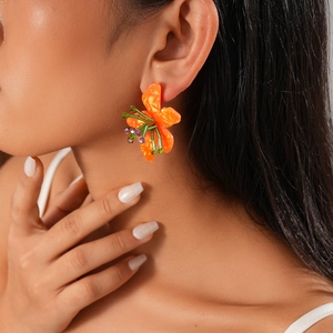 Close-up of orange resin flower earrings with green and purple beads on model's ear