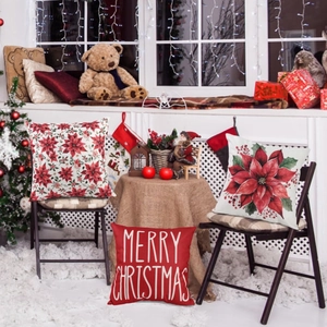 Three Christmas linen pillow covers with red floral designs on a festive indoor sofa