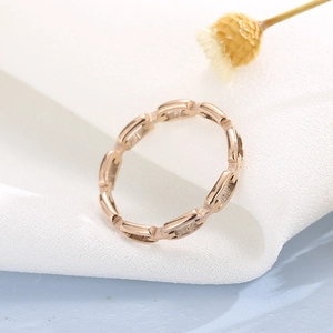 Macro shot of rose gold geometric chain ring on white linen with a yellow flower background