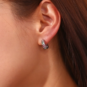 Gros plan de boucles d'oreilles en argent avec cristaux colorés portées à l'oreille