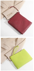 Detail of woven leather clutch bags in burgundy and lime green colors on beige blazer