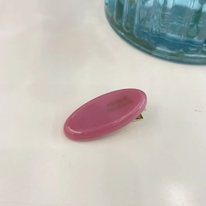 Detail of pink oval hair clip with France Handmade lettering and glossy finish