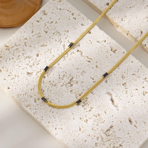 Detail of 18K gold plated snake chain necklace featuring a square black zircon pendant