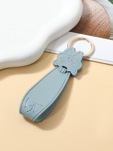 Detail of light blue PU leather pig keychain with golden metal ring on soft background