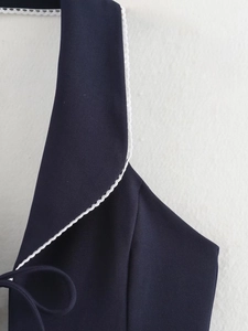 Détail du haut bleu marine sans manches avec dentelle blanche et col bénitier drapé