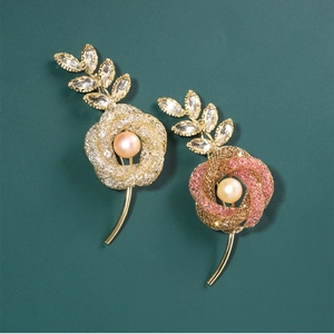 Detail of flower brooches with freshwater pearls and rhinestones on green background