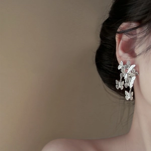 Detail of silver butterfly cluster earrings worn by model showing delicate metallic texture