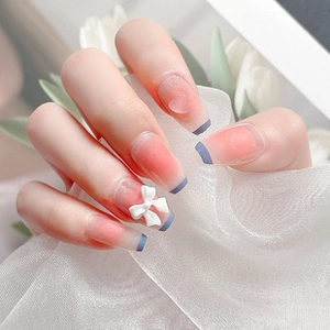 Detail of pink gradient long coffin nails with blue French tips and white bow charms