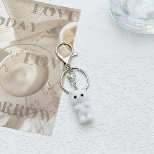 Cute white flocked cat keychain with pink ears and metal ring on artistic background