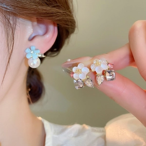 Detailed view of floral pearl earrings with blue petals and clear zircon accents