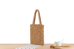 Detailed close-up of beige cotton rope woven tote bag on a wooden table with decor
