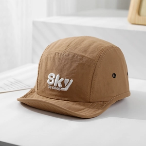 Detail van bruine sneldrogende babycap met wit Sky SO GOOD borduursel en metalen oogjes