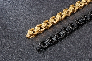 Detail of gothic skull bracelets in matte black and gold finishes with embossed wings