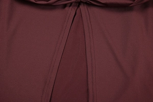 Detail view of double-needle stitching and split hem on deep wine red fabric