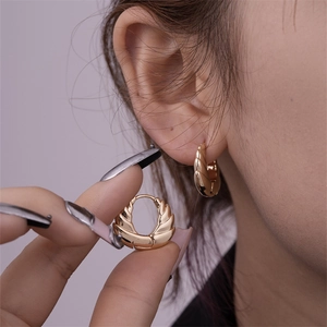 Detailed close-up of chunky gold hoop earrings with vintage feather embossed texture