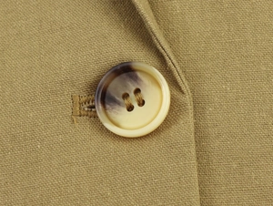 Close-up of tortoise shell resin button and khaki linen fabric texture on blazer