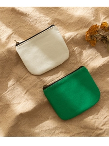 Detailed top view of minimalist beige and green canvas coin purses on rustic fabric